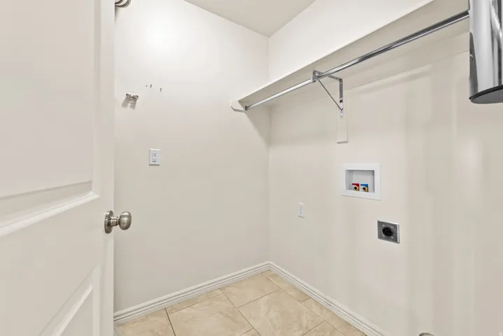 Utility area featuring ceramic tile flooring, a wall-mounted shelf, and a chrome hanging rod