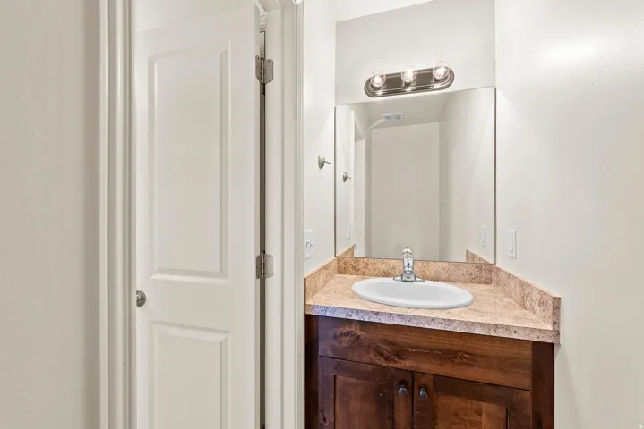 Vanity with a wood-finish cabinet, a single basin sink, and a speckled countertop