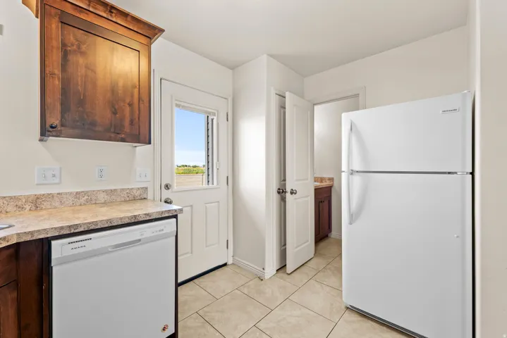 Kitchen area featuring tile flooring, a white dishwasher, and a white refrigerator