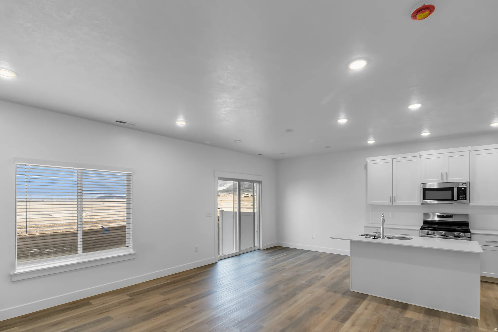 Open-concept living space featuring wood-finish flooring, recessed lighting, and a sliding glass door