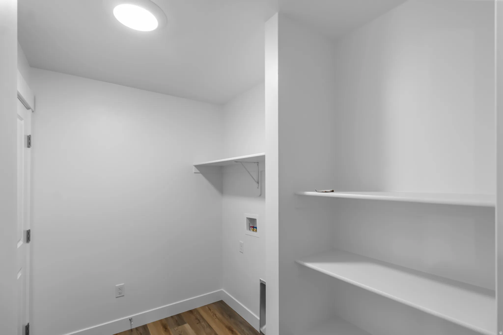 Dedicated laundry area featuring wood-finish flooring and a flush-mount ceiling light