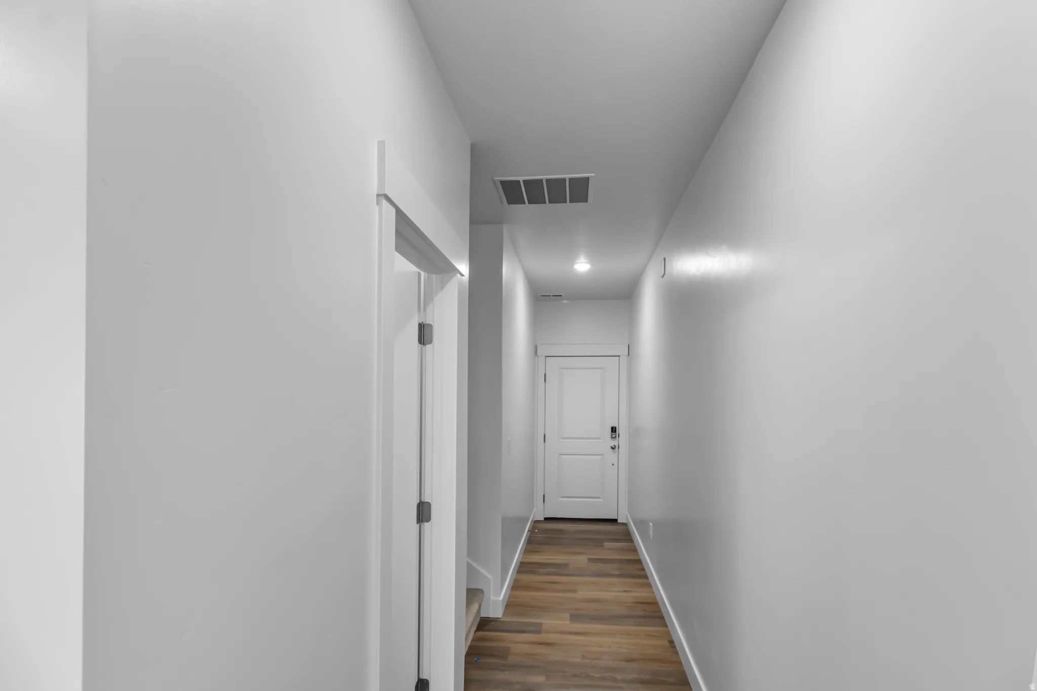 Hallway featuring wood-finish flooring, white walls, and recessed lighting