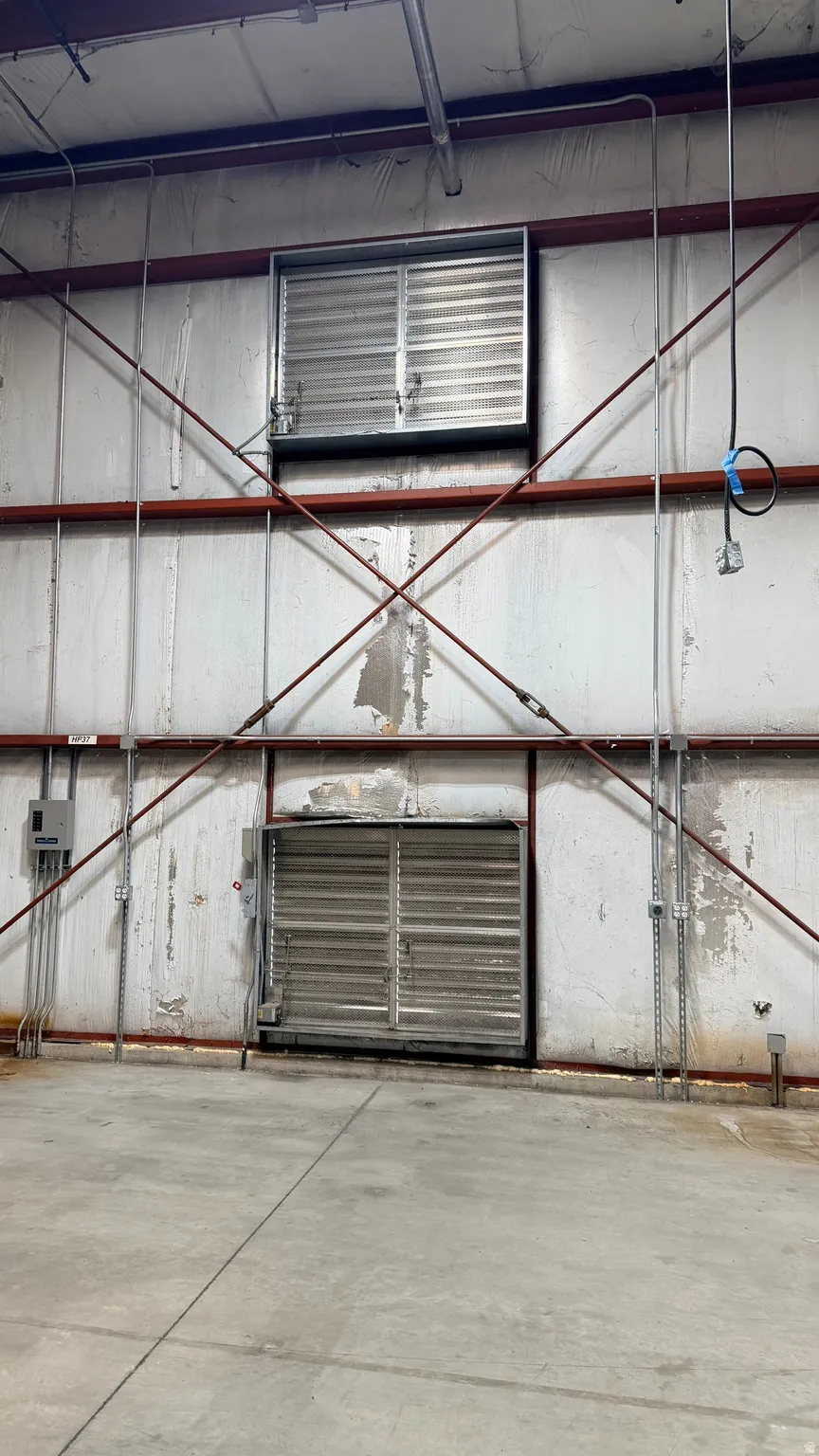 Industrial interior featuring two wall-mounted ventilation units, exposed structural beams, and a concrete floor