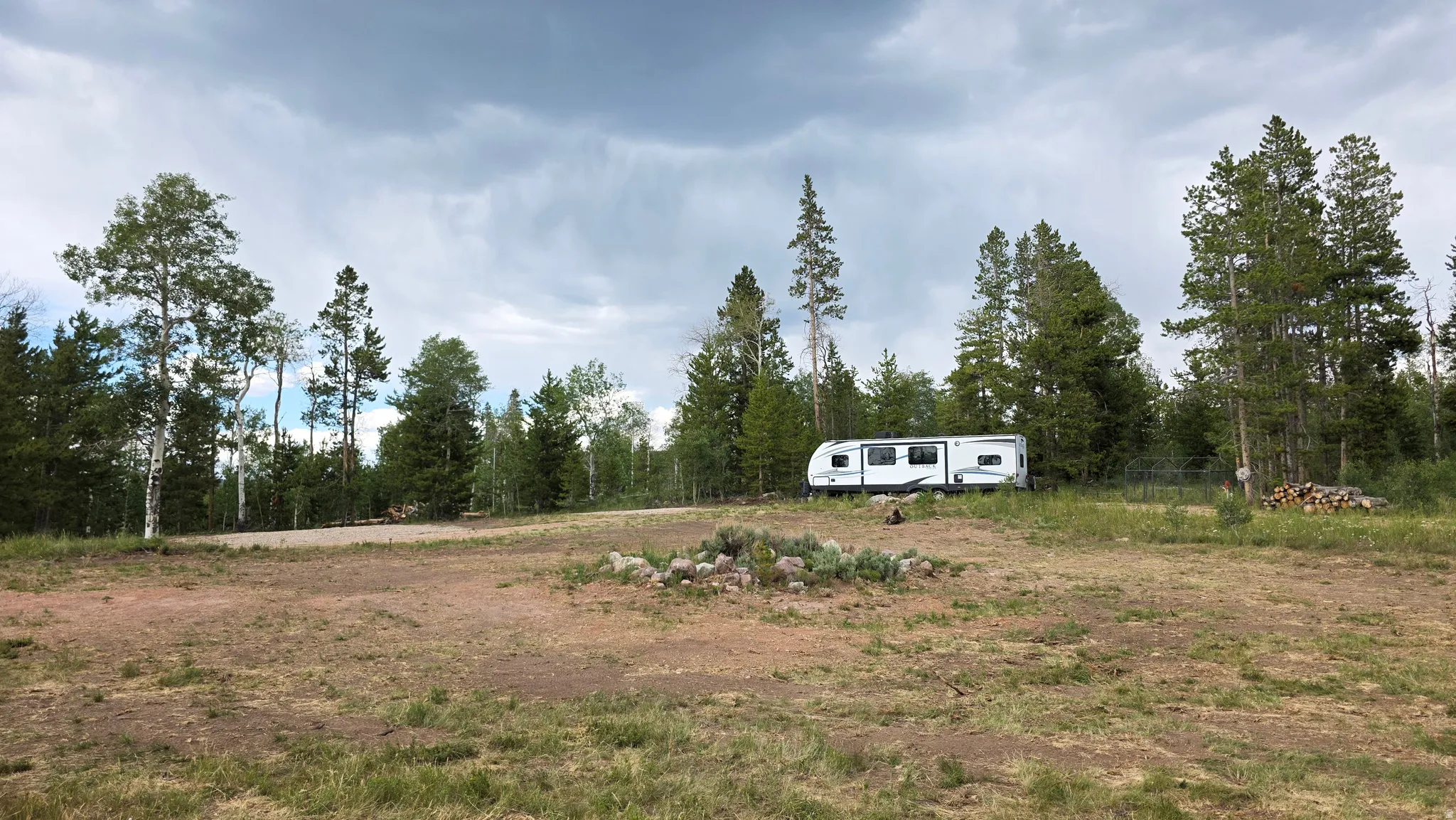 Expansive cleared lot surrounded by mature evergreen and deciduous trees