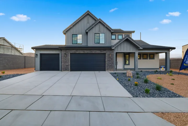 Contemporary two-story residence featuring a board and batten facade, stone accents, a covered entry porch, two-car garage with dark paneled doors, and a concrete driveway