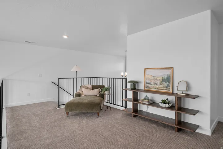 Upper-level landing featuring carpet flooring, crisp white walls, recessed lighting, and a contemporary black metal railing