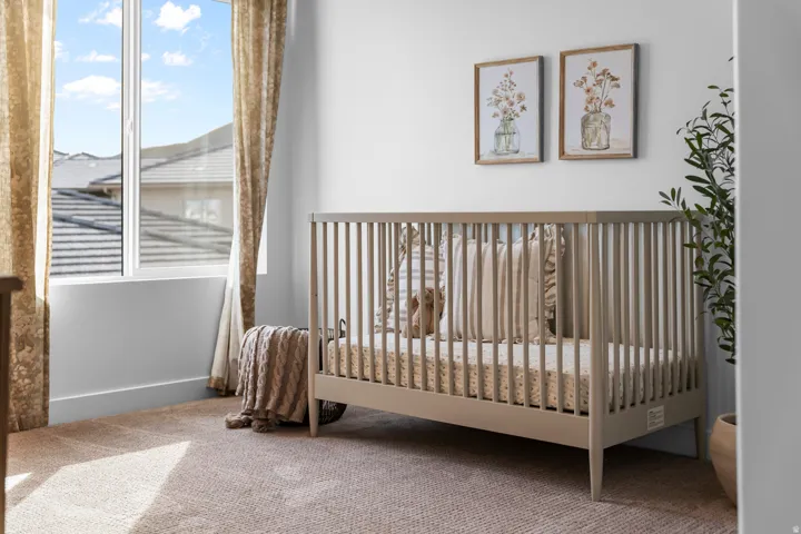 Bright room featuring a large window with white framing, beige textured carpet, and neutral wall paint