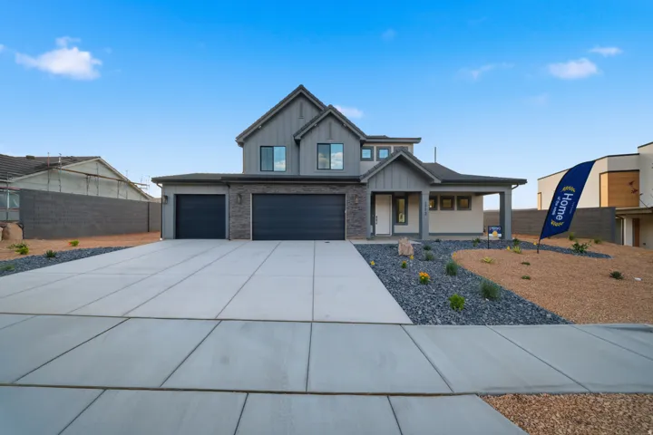 Contemporary exterior featuring board and batten siding, stone accents, a covered entry, and a two-car garage