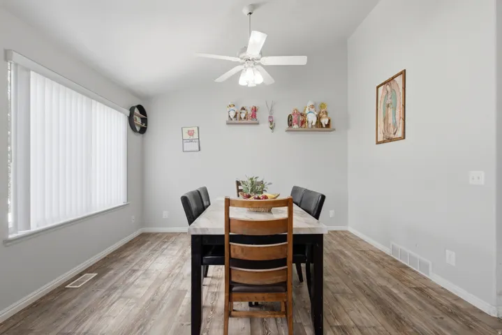 Dining area featuring wood-finish flooring, vaulted ceiling, and a ceiling fan with integrated lighting