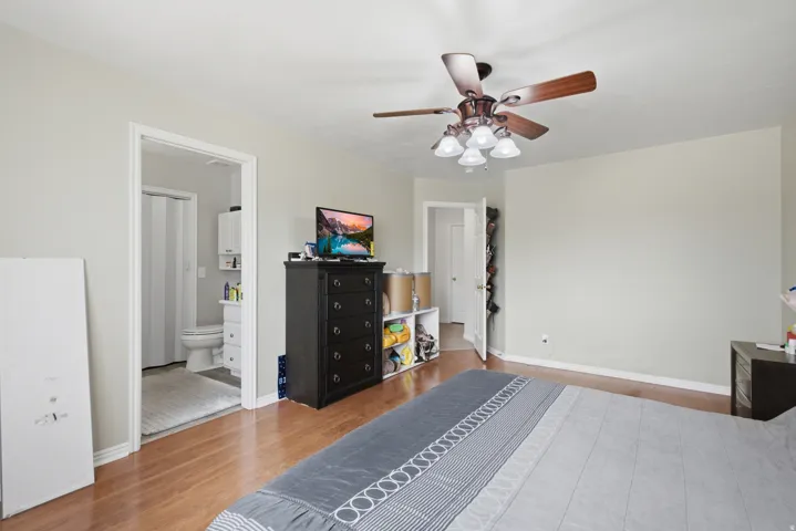 Bedroom featuring wood-finish flooring, a ceiling fan with integrated lighting, and light-toned walls