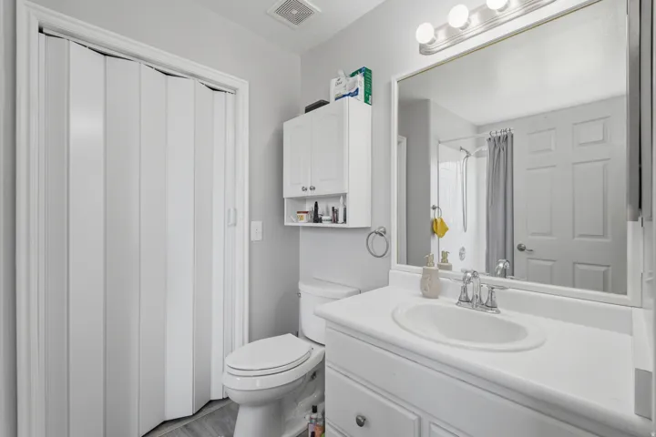 Bathroom featuring a white vanity with an integrated sink, chrome faucet, and a large mirror with a three-bulb light fixture