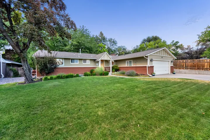Ranch-style residence featuring a prominent front lawn, two-tone exterior siding, brick detailing, and an attached single-car garage