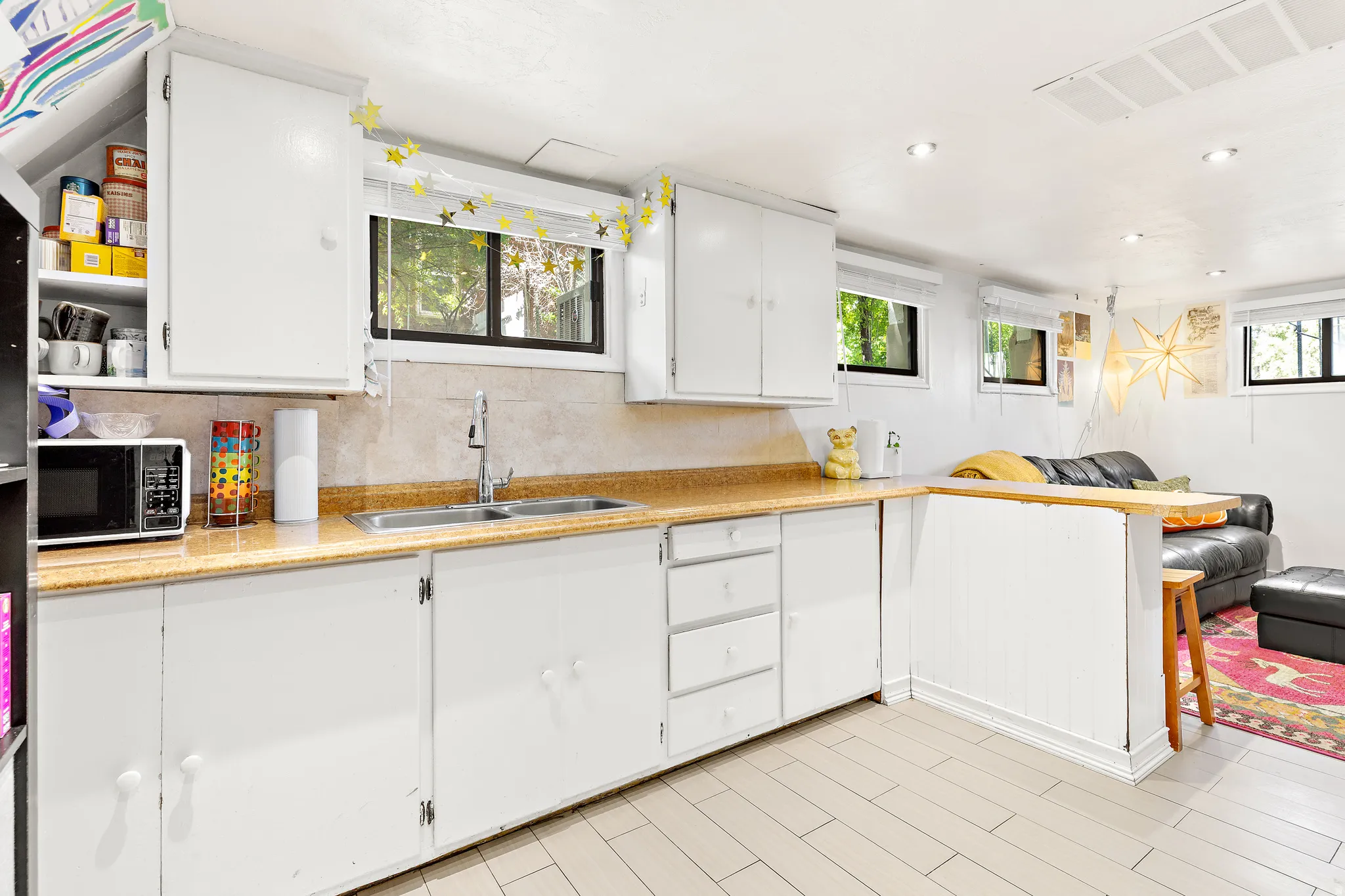 Kitchenette featuring white cabinetry, a double basin stainless steel sink, and light-toned countertops