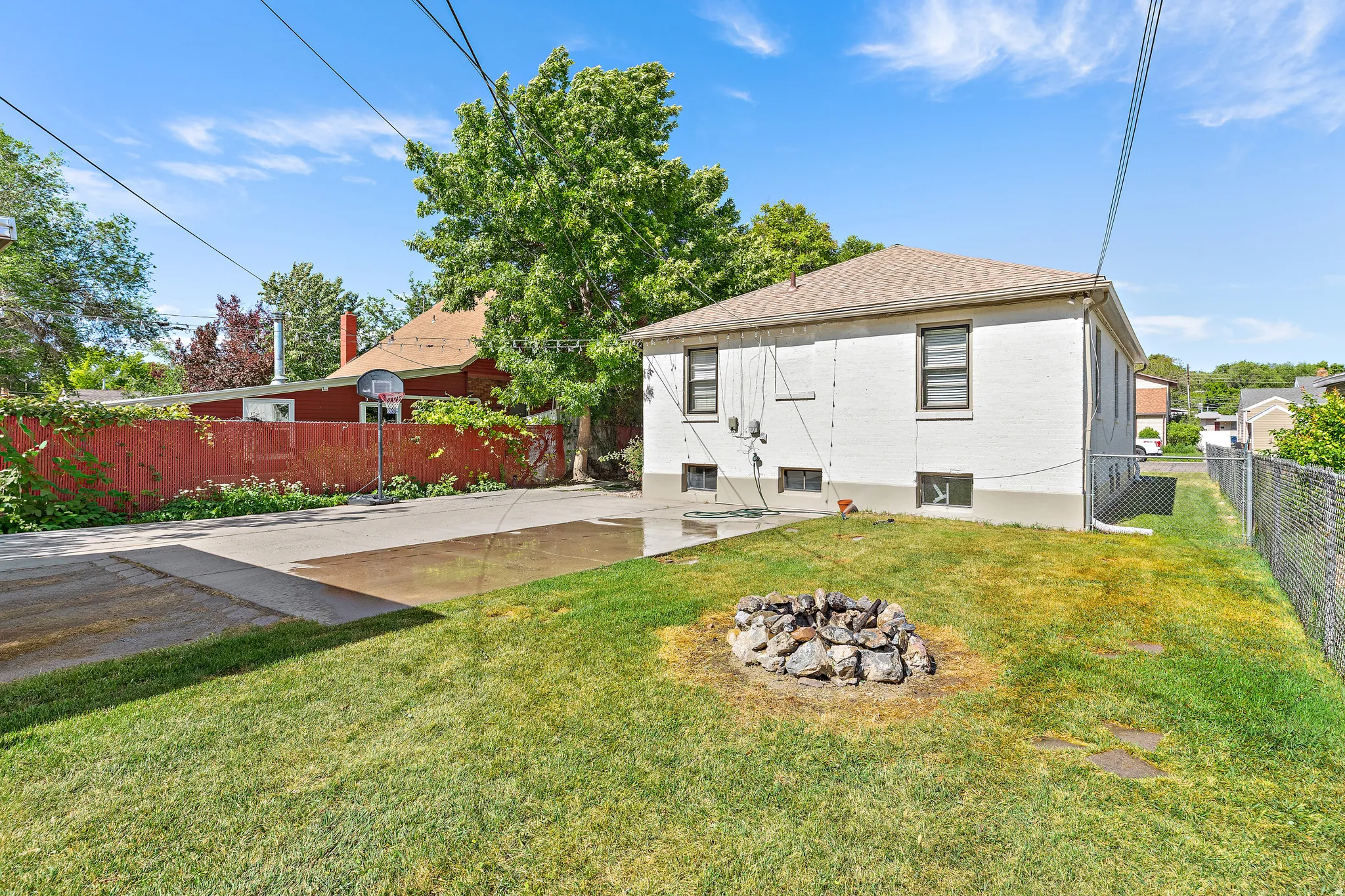 Expansive backyard featuring a lush lawn, stone fire pit, and a paved patio area