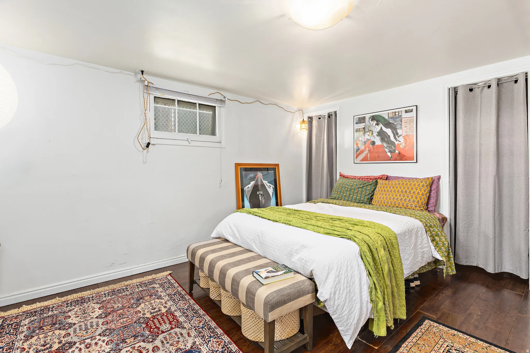 Room featuring dark wood-finish flooring, a flush-mount ceiling light fixture, and a window with security bars