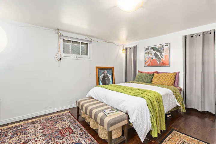 Room featuring dark wood-finish flooring, a flush-mount ceiling light fixture, and a window with security bars