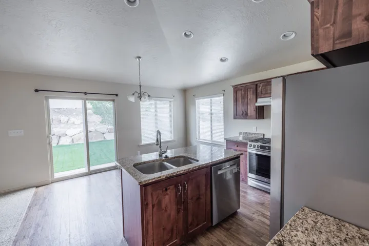 Kitchen with wood-finish flooring, granite countertops, and stainless steel appliances