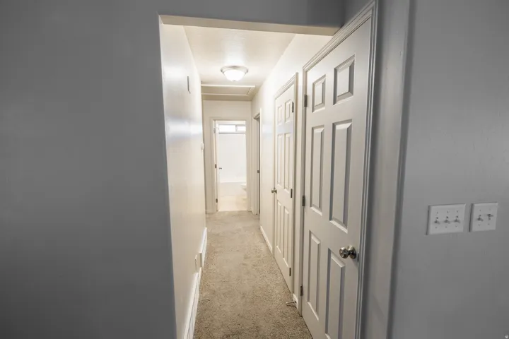 Hallway featuring neutral-toned carpet flooring and white painted walls