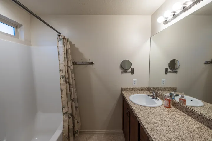 Dual vanity with an integrated basin sink, speckled countertop, and full-width mirror