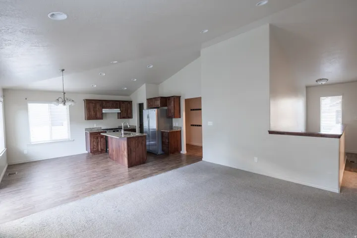 Vaulted ceilings, wood-finish flooring, recessed lighting, wood cabinetry, and stainless-steel appliances