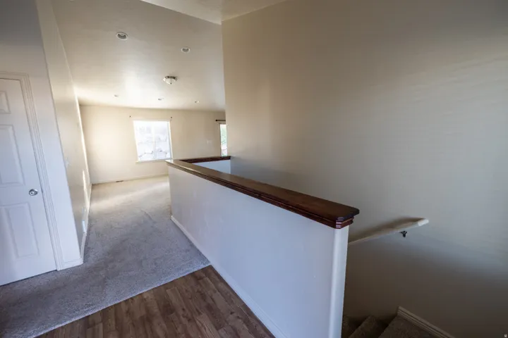 Recessed ceiling lighting, wood-finish flooring, half-wall with wood-finish cap, and a white interior door