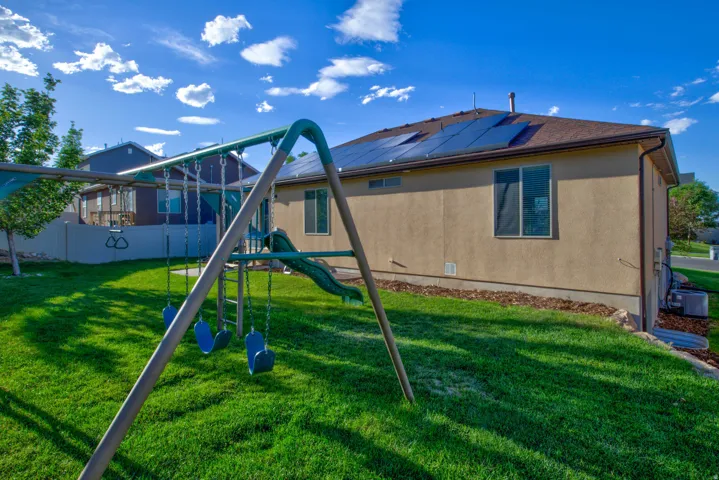 Expansive backyard featuring a manicured lawn, a swing set with slide, and a durable privacy fence