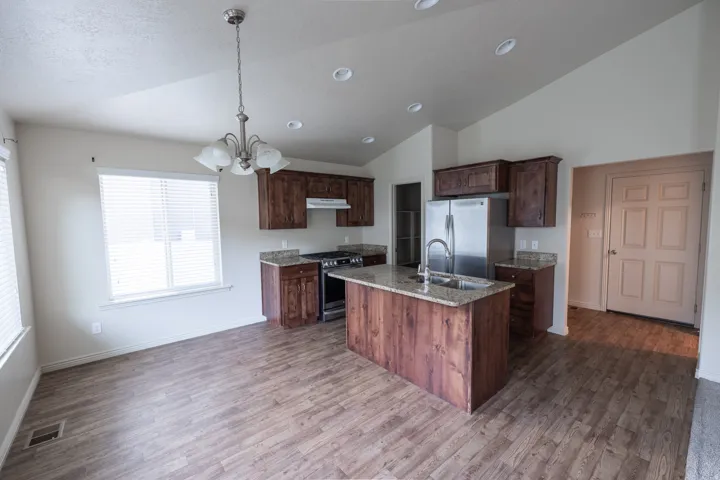 Open-concept kitchen with wood-finish flooring, vaulted ceilings, and recessed lighting