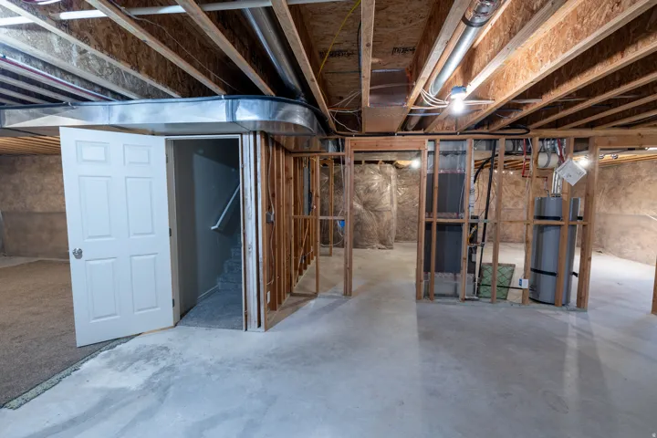Unfinished basement with concrete flooring, exposed ceiling joists, and structural framing