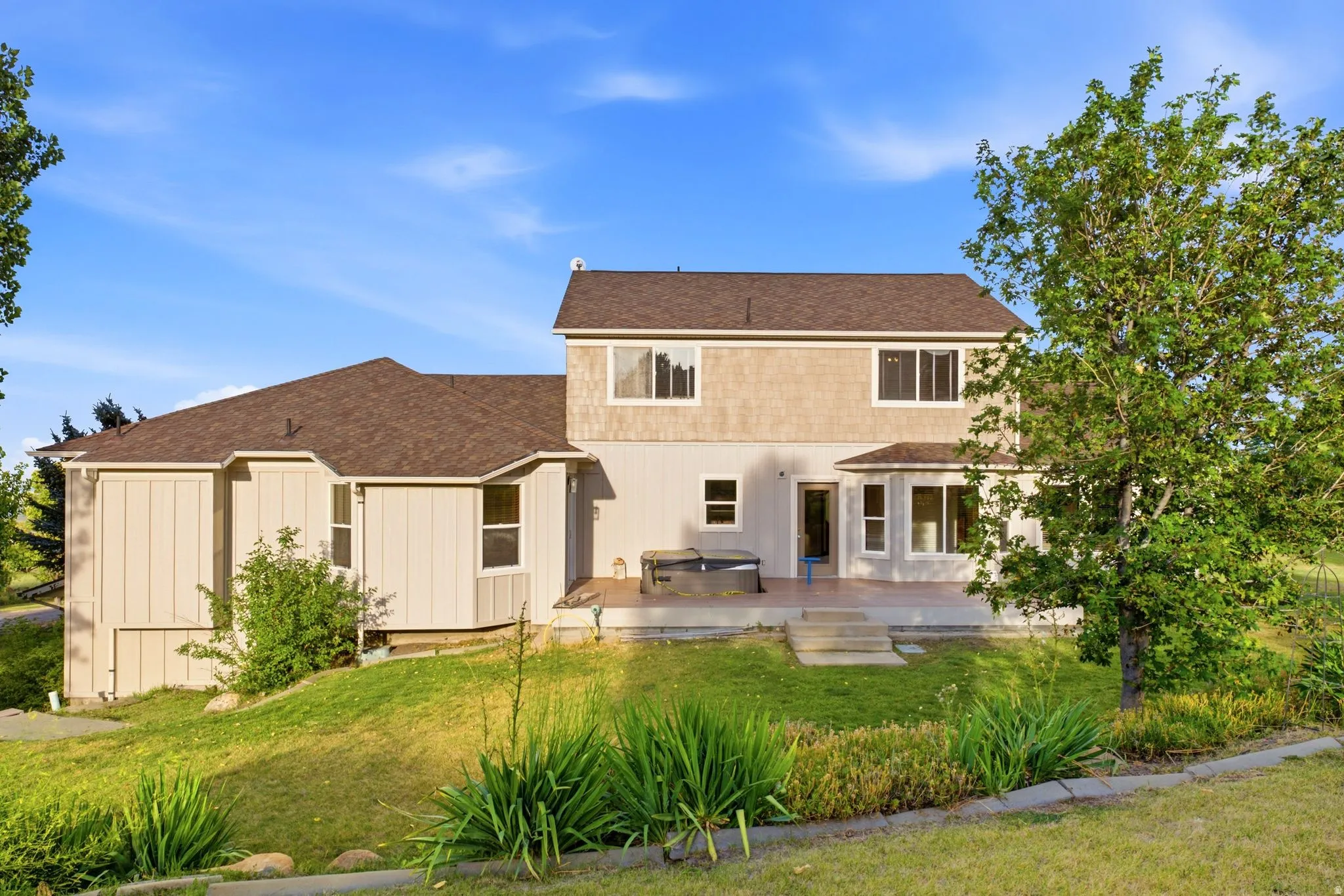 Rear exterior featuring a spacious patio, multiple windows, and a tiered lawn