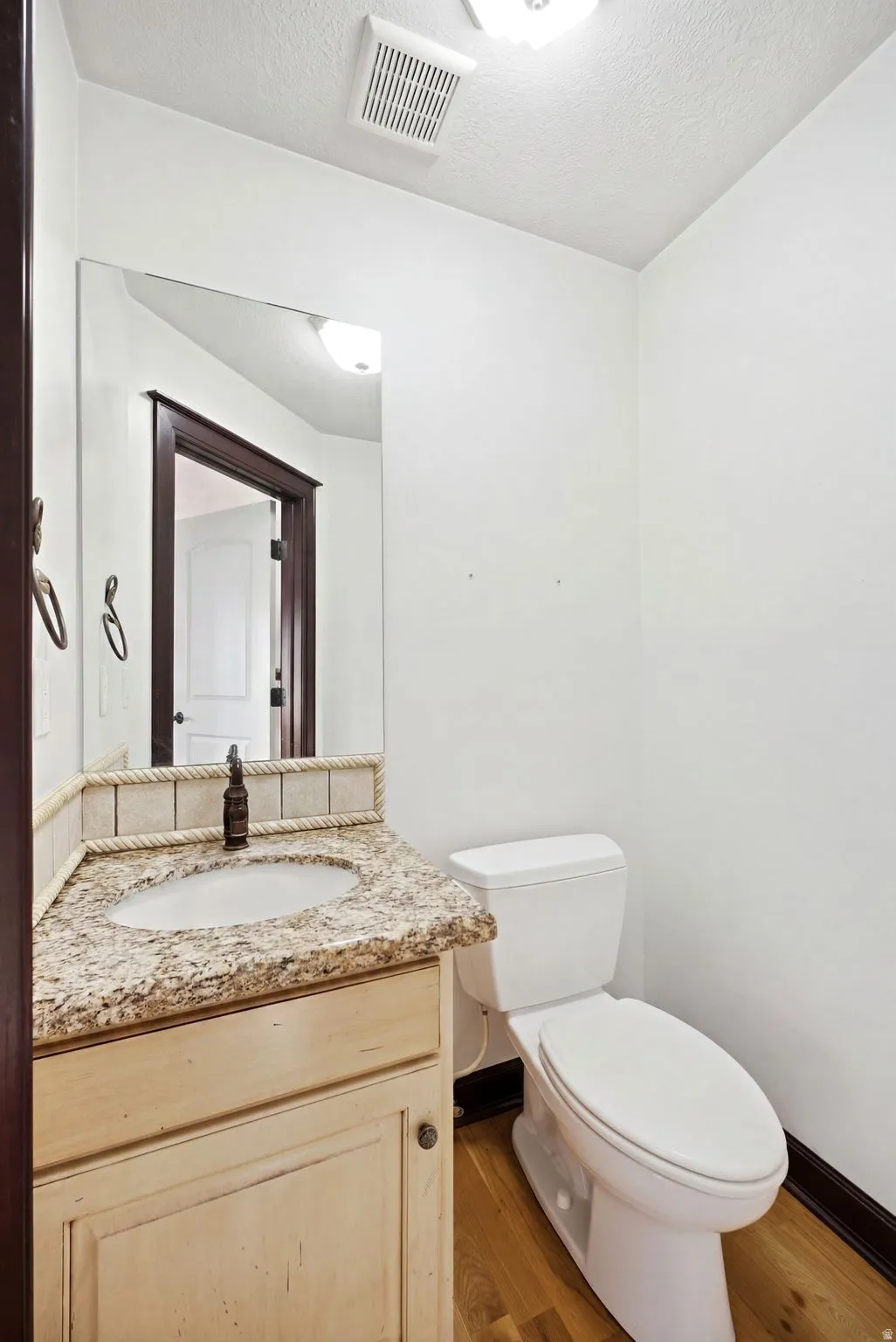 Main home off the kitchen. Powder room featuring a light-toned vanity with a granite-finish countertop and an undermount sink