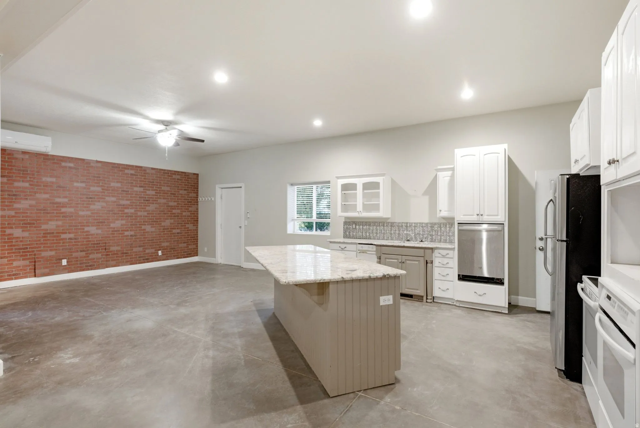 Kitchen in the apartment in the shop. Open-concept living space featuring a brick accent wall, concrete flooring, and recessed lighting