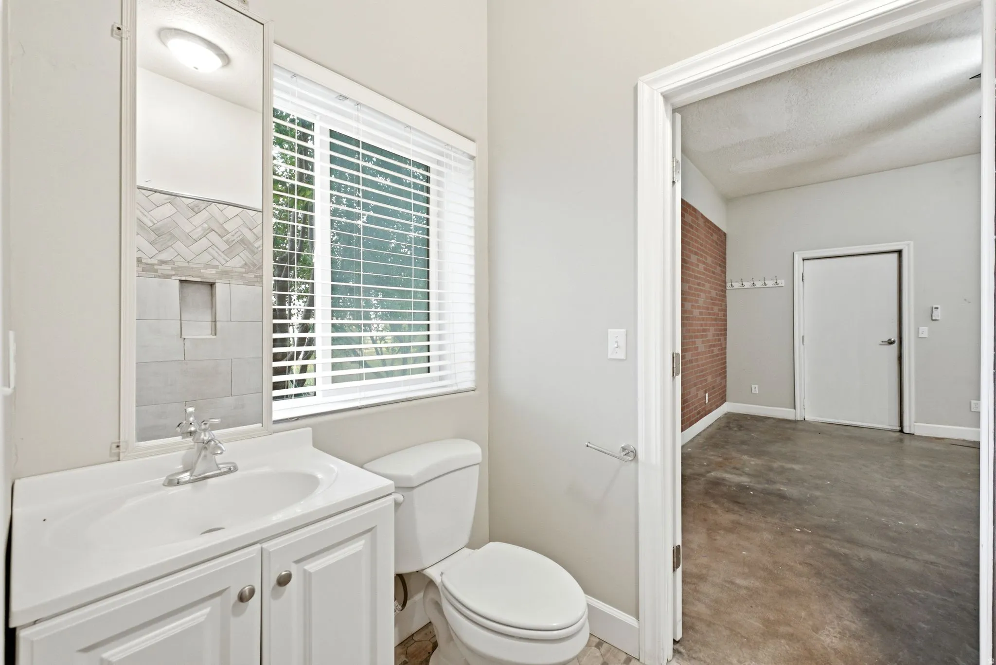 Full bathroom featuring a white vanity with integrated sink, chrome faucet, and a wall-mounted mirror