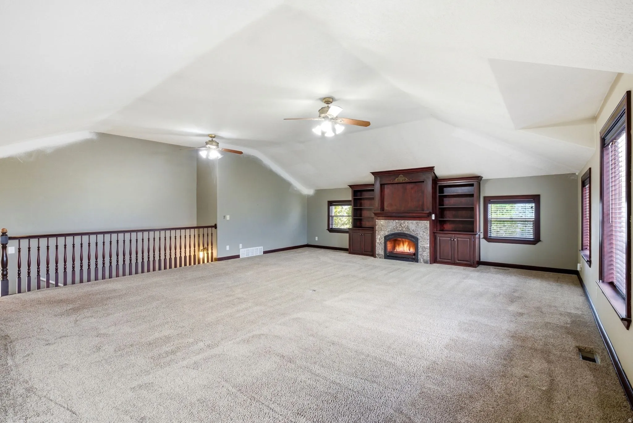 Spacious open room featuring a vaulted ceiling, ceiling fans, and neutral carpet