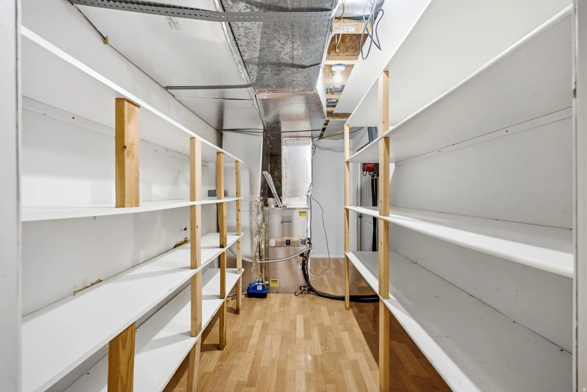 Main home basement. Utility room featuring extensive built-in shelving, wood-finish flooring, and exposed ductwork