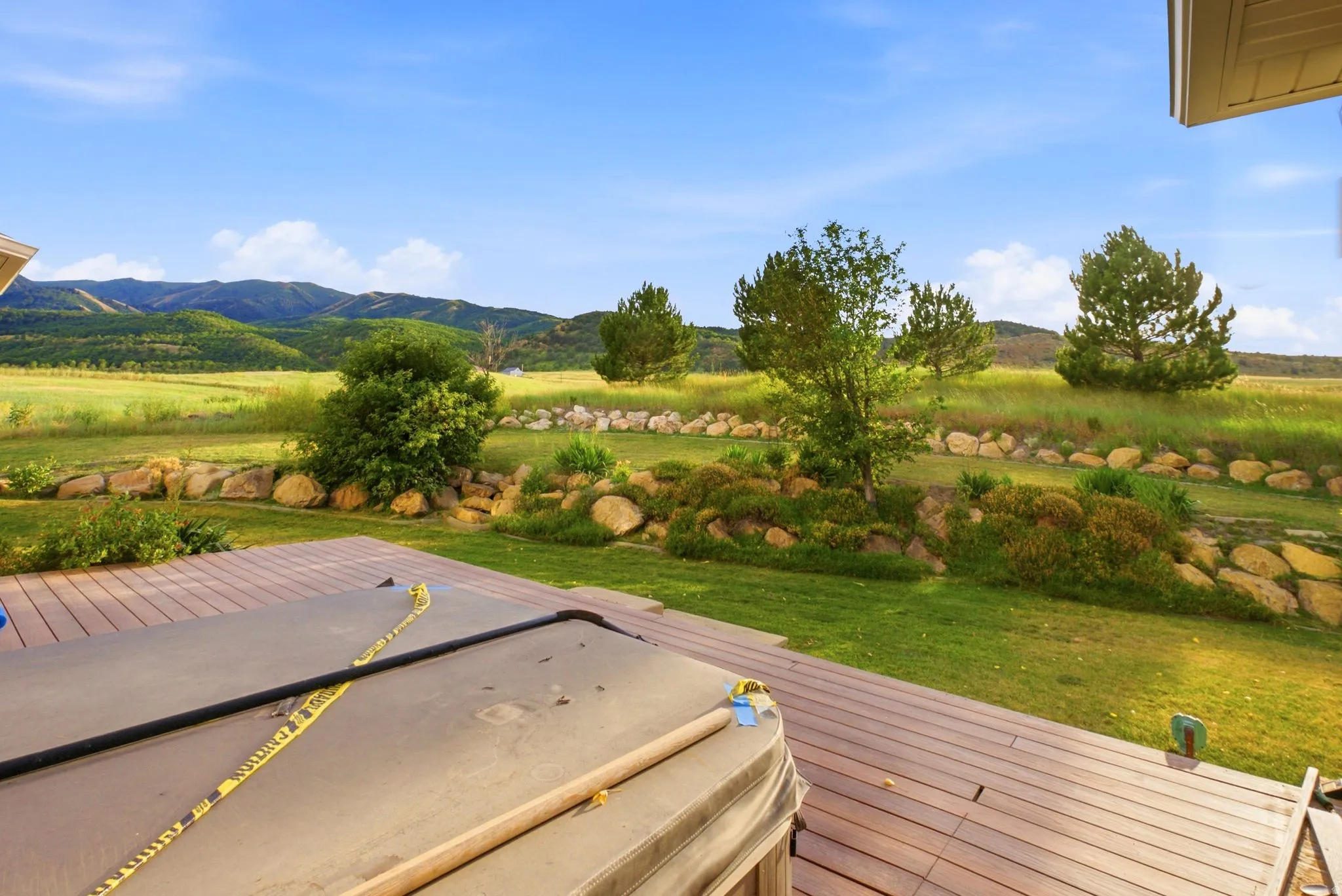 Expansive wood-finish deck overlooking a verdant lawn and distant mountains