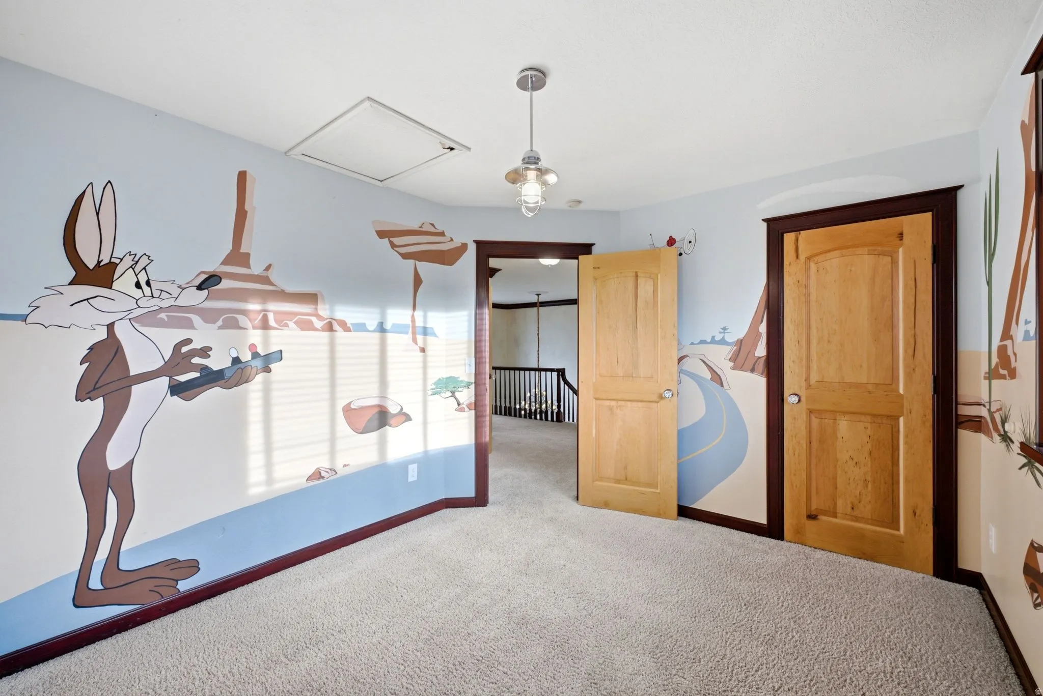 Upstairs bedroom. Carpeted room featuring custom mural wall art, natural wood doors with dark trim, and a ceiling-mounted light fixture