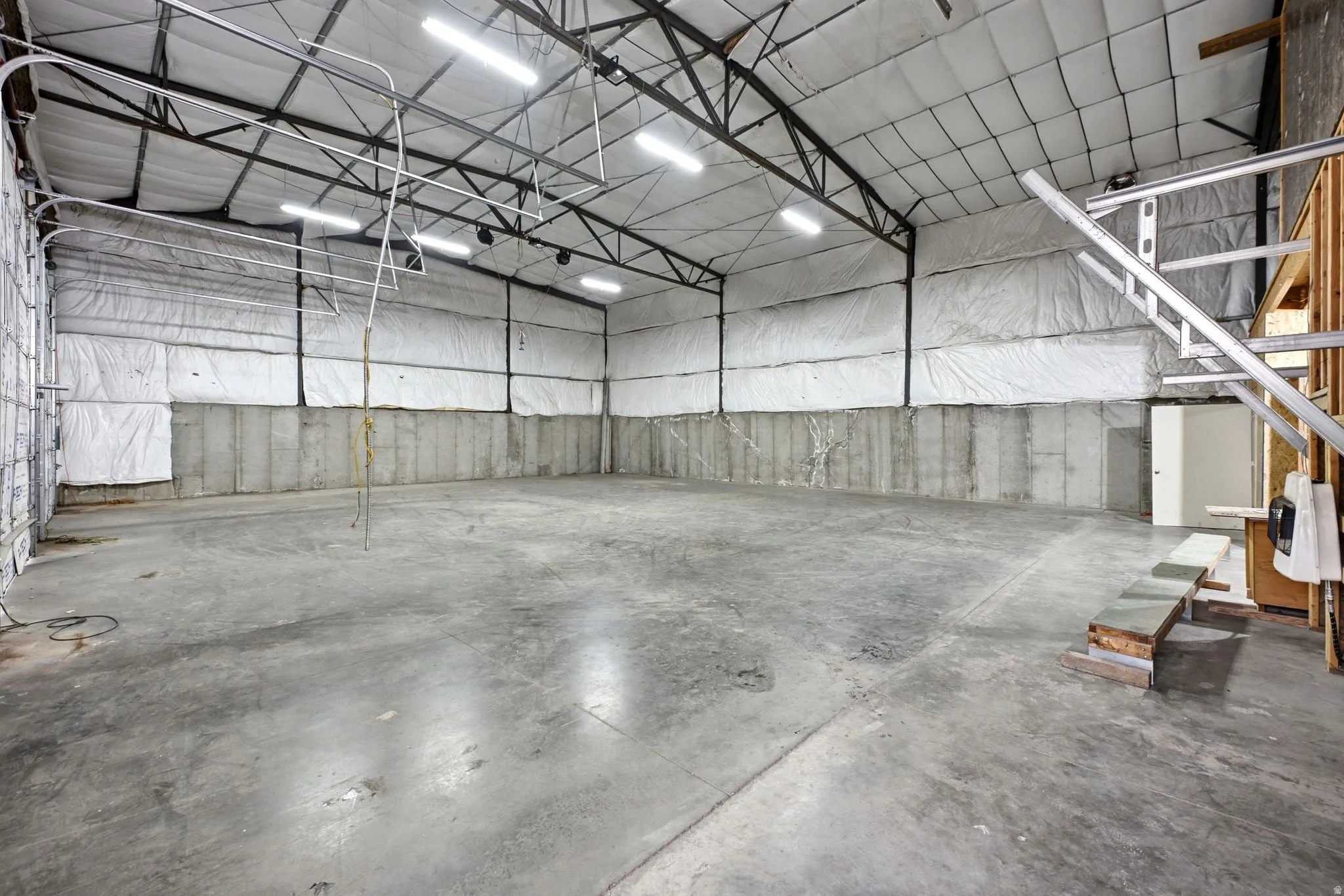 Expansive warehouse space featuring a concrete floor, concrete block walls, and insulated upper walls