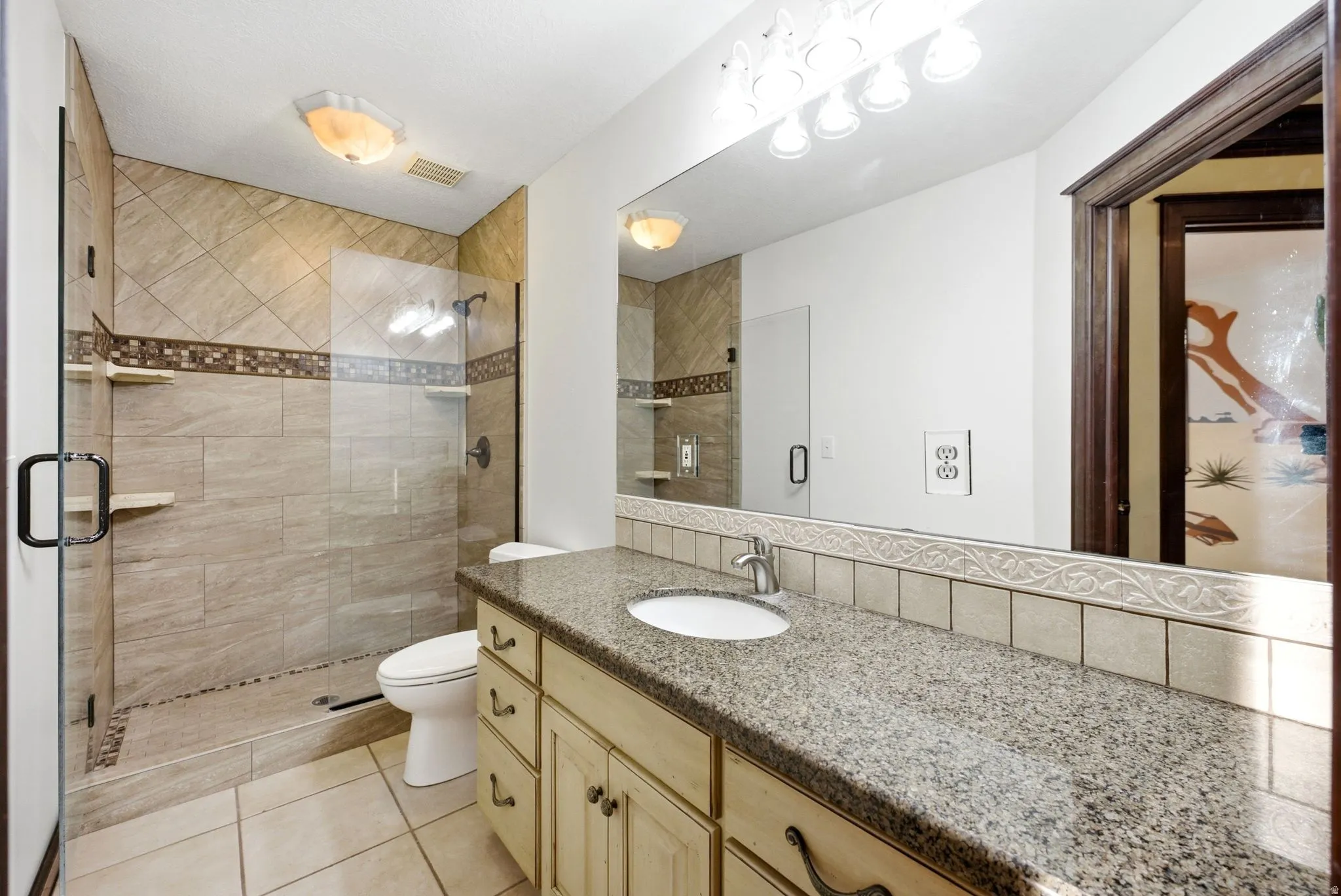 Main home upstairs. Full bathroom featuring a walk-in shower with glass enclosure, beige ceramic tile, and decorative accent banding