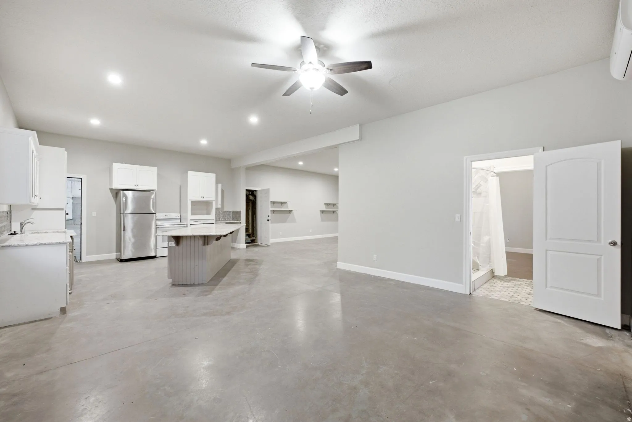 Open-concept living area featuring polished concrete flooring, recessed lighting, a ceiling fan, and light gray wall tones