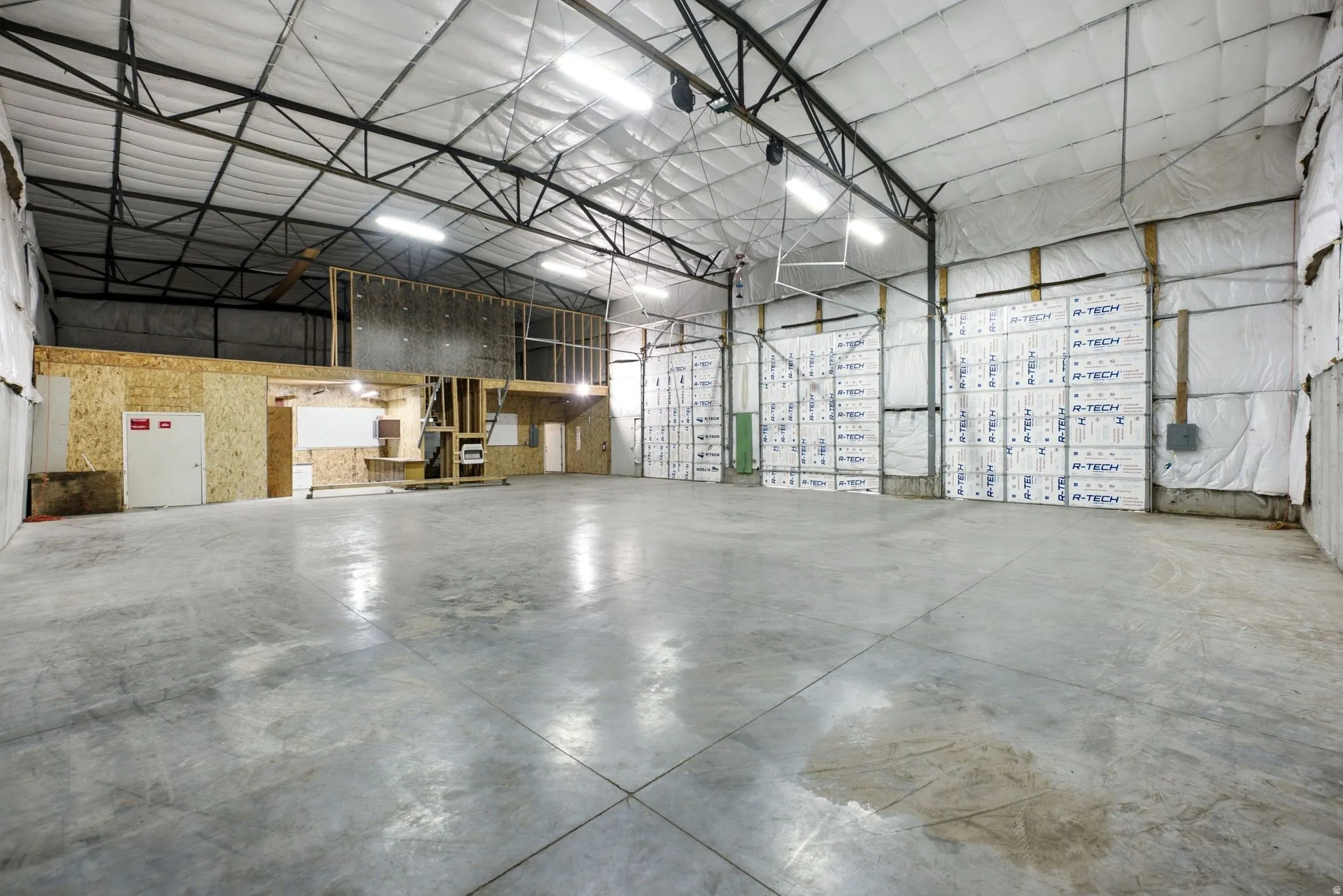 Expansive concrete flooring in a large open warehouse space with exposed metal truss ceiling