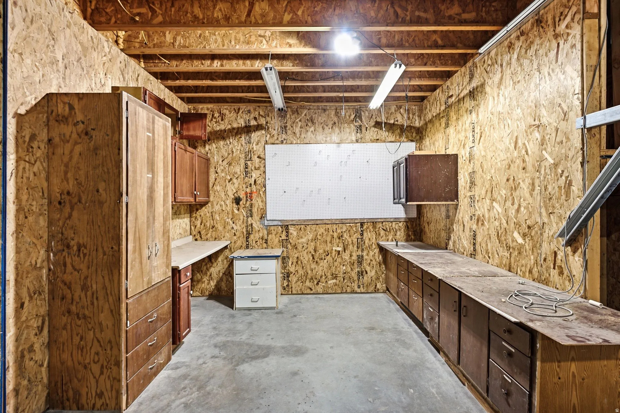 Utility room featuring wood-finish cabinetry, ample countertop space, and overhead fluorescent lighting