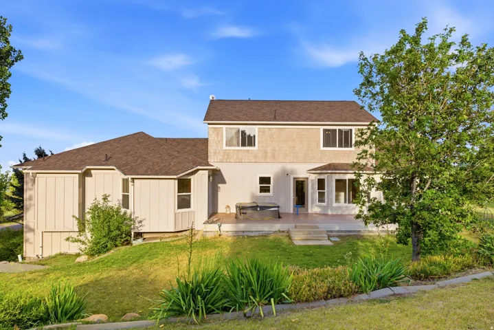 Rear exterior featuring a spacious patio, multiple windows, and a tiered lawn