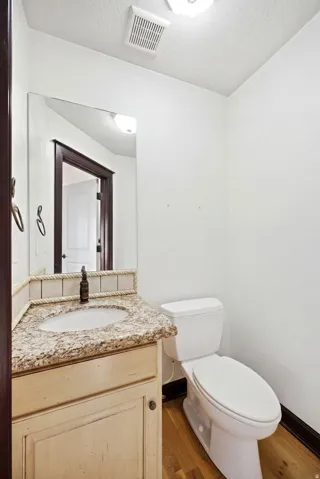 Main home off the kitchen. Powder room featuring a light-toned vanity with a granite-finish countertop and an undermount sink