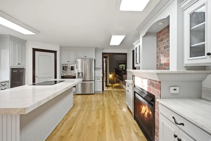 Spacious kitchen featuring light wood-finish flooring and an expansive center island with a cooktop and light-toned countertop