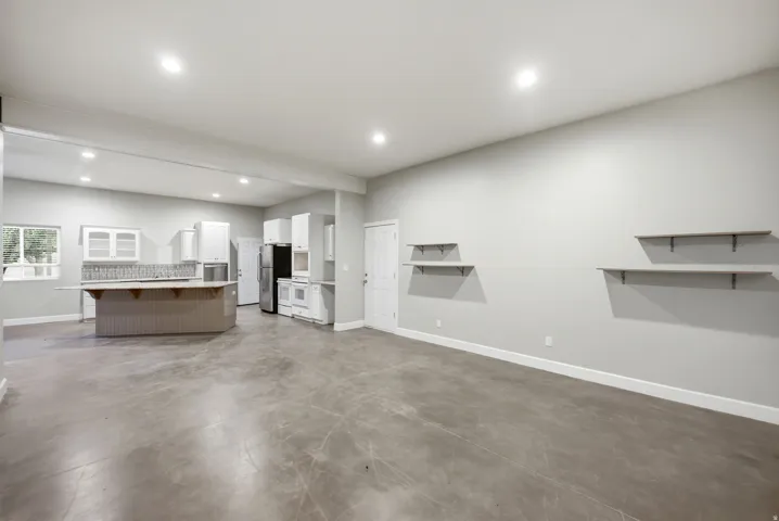 Apartment in the shop. Open concept living area featuring a kitchen with white cabinetry, a central island with counter seating, a tiled backsplash, and recessed lighting