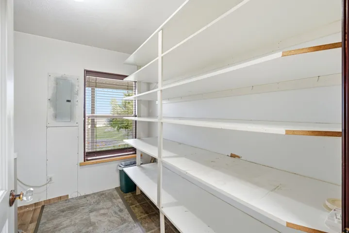 Spacious 2nd kitchen pantry with extensive built-in white shelving, a window with horizontal blinds, and durable tile flooring