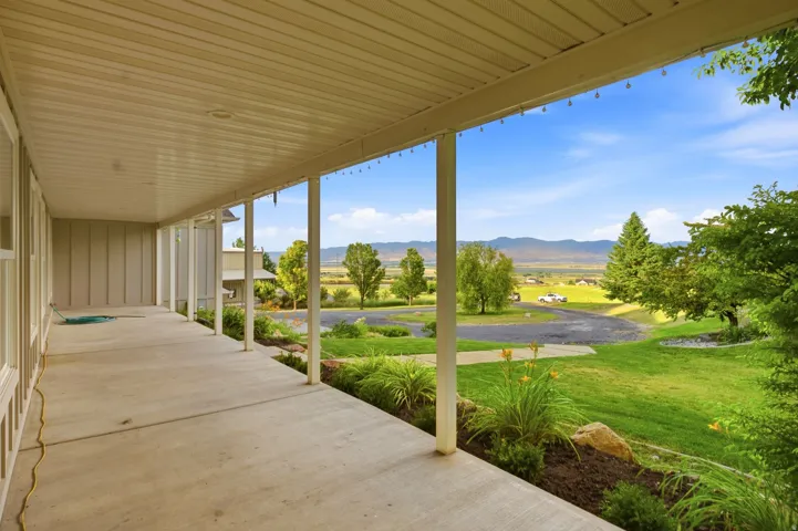 Expansive covered porch with a concrete slab, multiple support pillars, and a tongue and groove ceiling