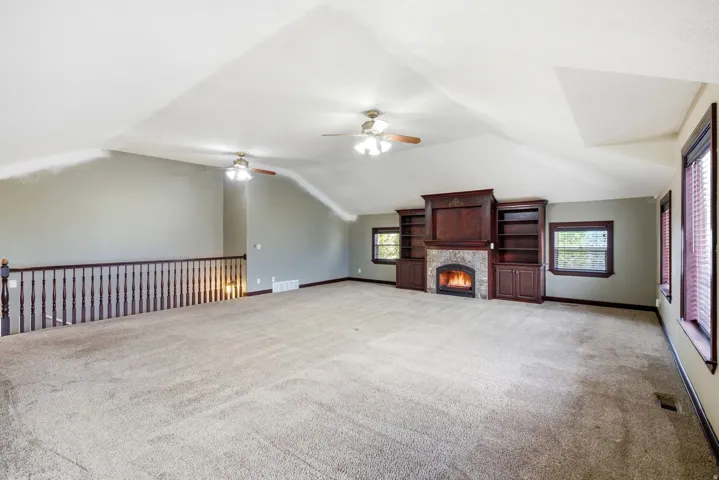 Spacious open room featuring a vaulted ceiling, ceiling fans, and neutral carpet