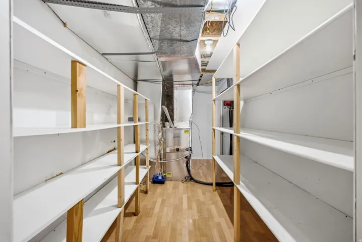 Main home basement. Utility room featuring extensive built-in shelving, wood-finish flooring, and exposed ductwork