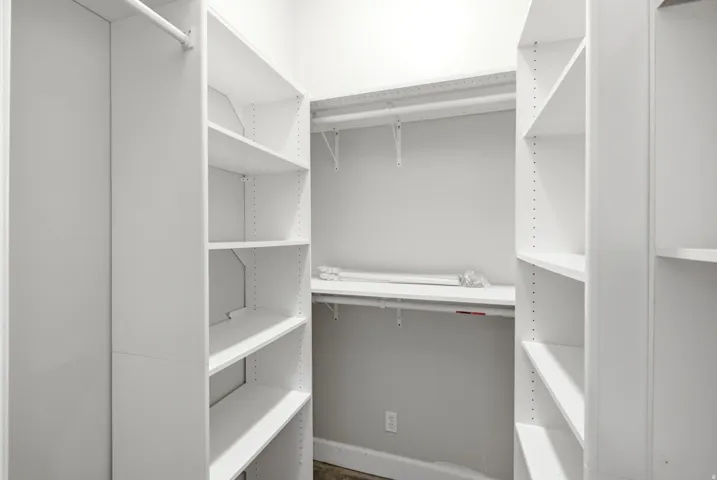 Apartment in the shop. Walk-in closet featuring white shelving units, multiple hanging rods, and adjustable shelves